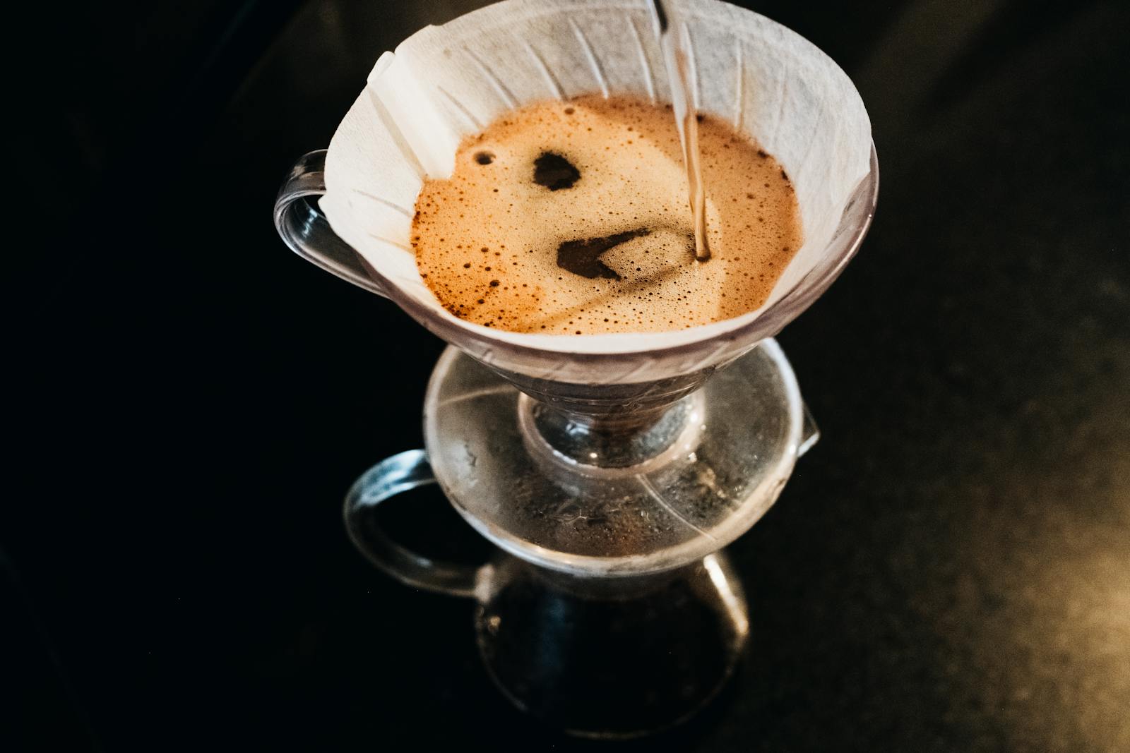 Hand pouring water from a gooseneck kettle into a pour-over coffee dripper