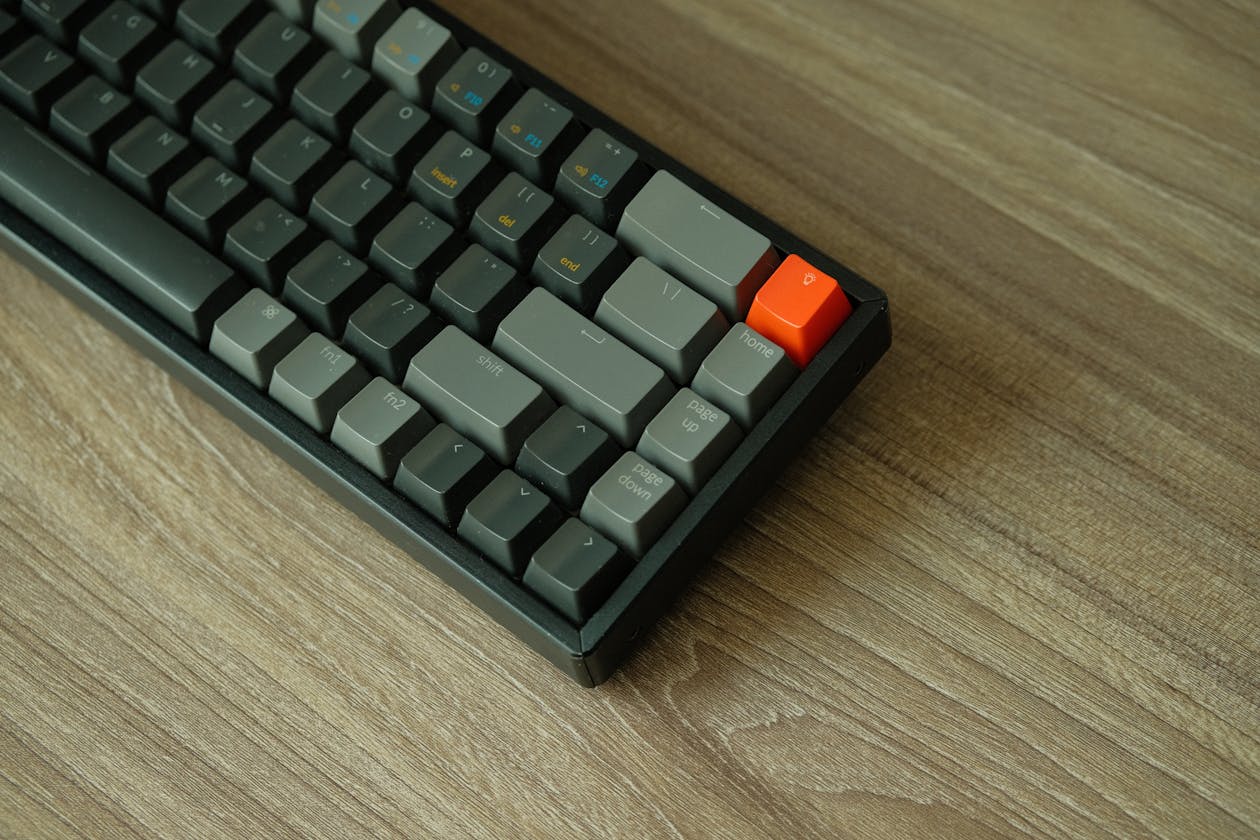 Mechanical keyboard with orange accent key on wooden desk
